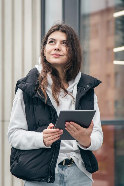 寒い日に外でタブレットを持っているビジネスの若い女性