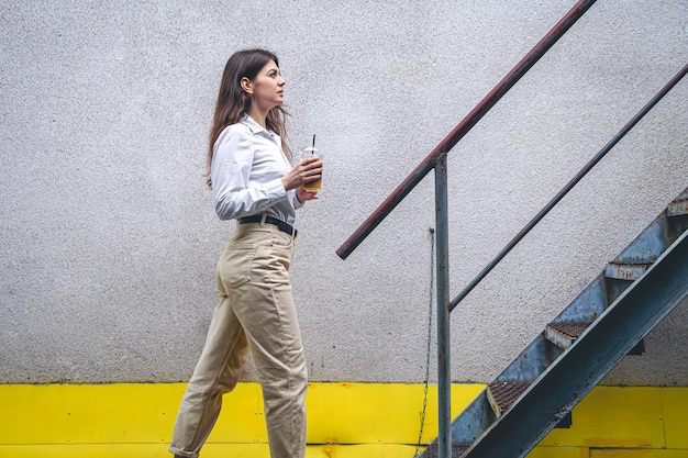 Business young woman near the stairs with a cup of coffee