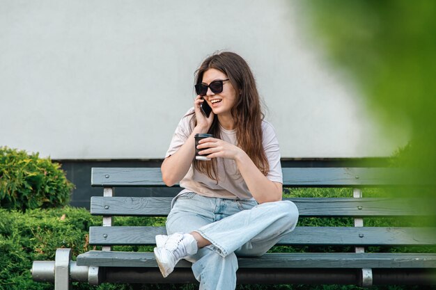 Business young woman sits on a bench and speaks on the phone