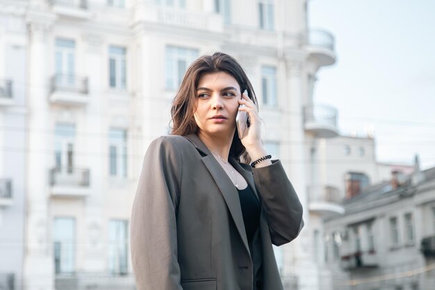 도시의 흐릿한 배경에 스마트폰을 들고 있는 비즈니스 젊은 여성