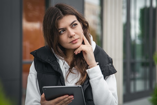 Free photo business young woman with a tablet on the background of the building