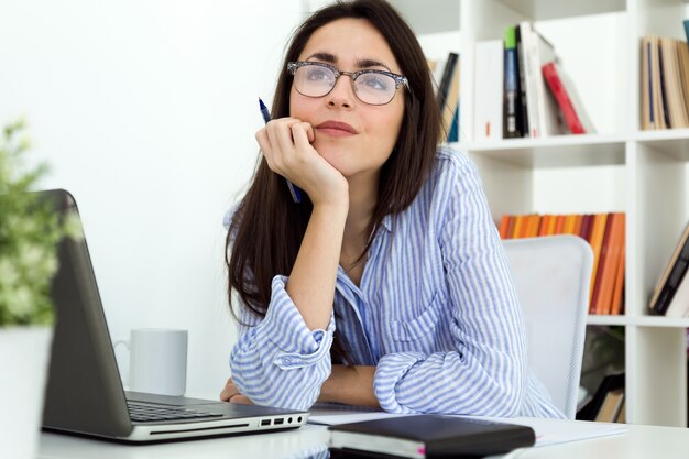 ビジネスの若い女性は、オフィスでラップトップを使用しています。