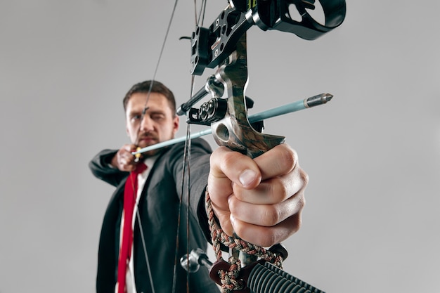 Businessman aiming at target with bow and arrow, isolated on white background