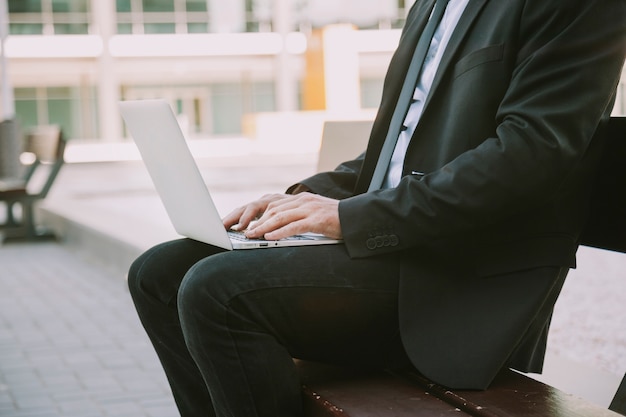 Free photo businessman on bench with laptop