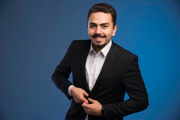 Businessman in black suit buttoning his blazer. 