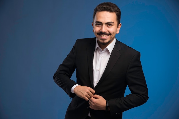 Businessman in black suit buttoning his blazer.