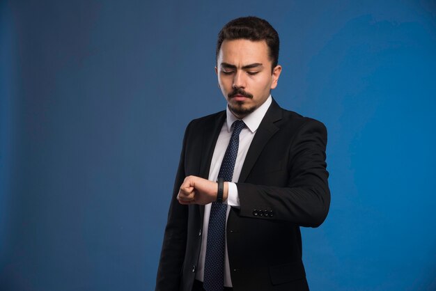 Businessman in black suit checking his time.