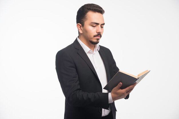 Businessman in black suit holding his tasklist and checking it. 