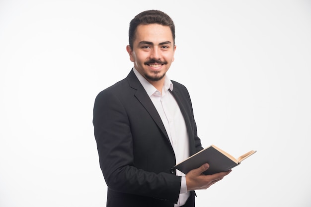 Businessman in black suit holding his tasklist and smiling.