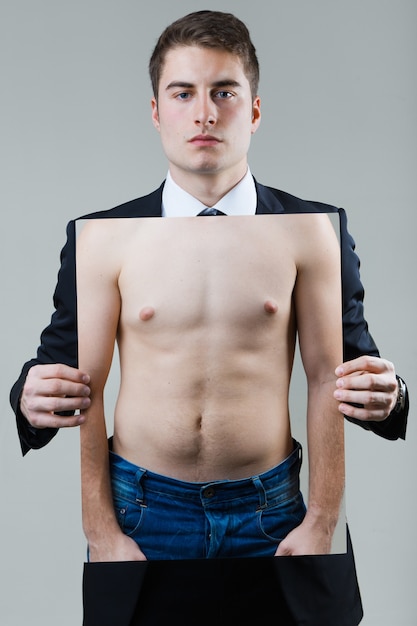 Businessman in black suit holding a photo of a naked male torso.