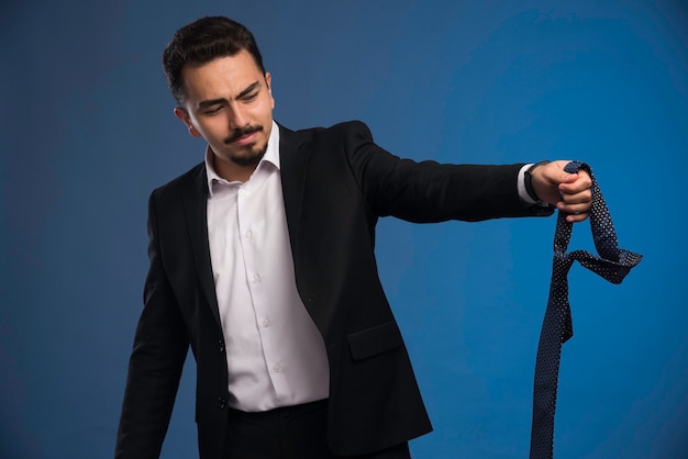 Businessman in black suit holding a tie. 