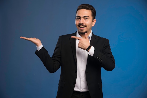 Businessman in black suit pointing to something. 