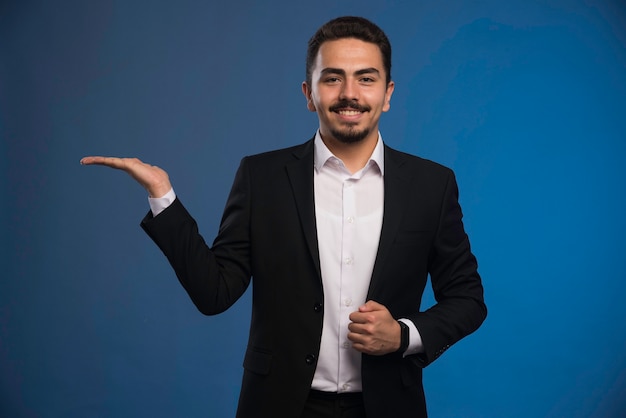 Businessman in black suit promoting something.