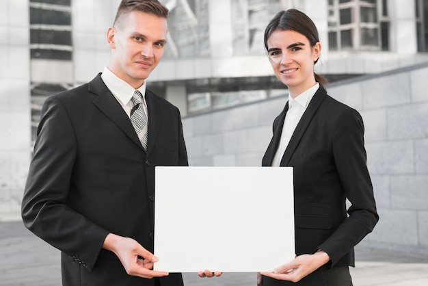 Businessman and businesswoman holding blank paper template