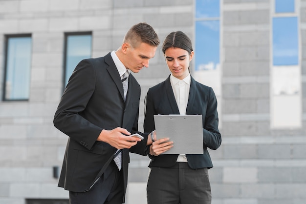 Businessman and businesswoman looking at clipboard