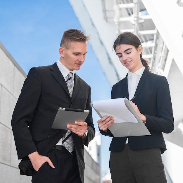 Businessman and businesswoman looking at clipboard