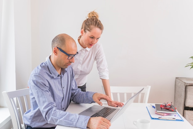 Businessman and businesswoman looking at laptop