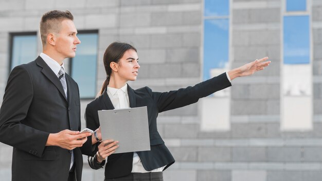 Businessman and businesswoman pointing somewhere