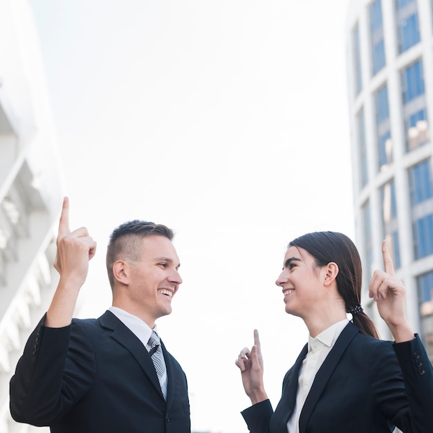 Businessman and businesswoman pointing upwards