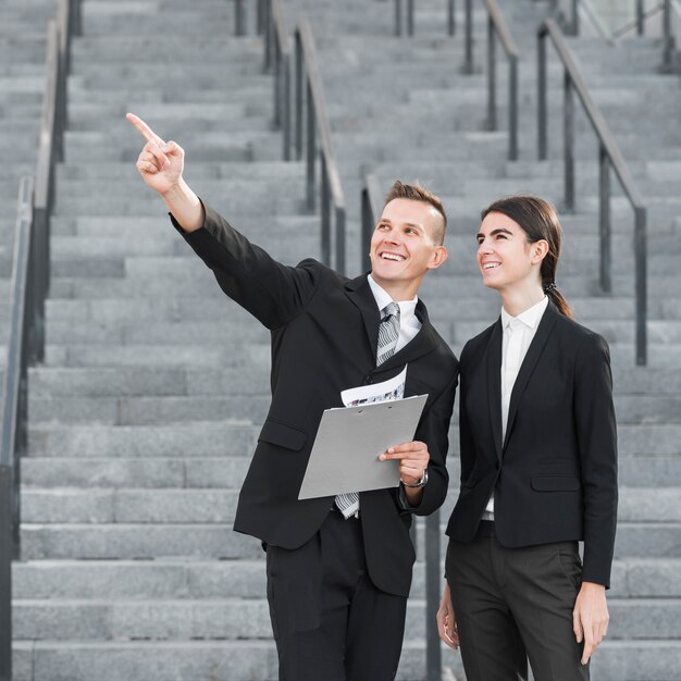 Businessman and businesswoman pointing upwards