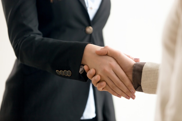 Businessman and businesswoman shaking hands, business handshake close up view 