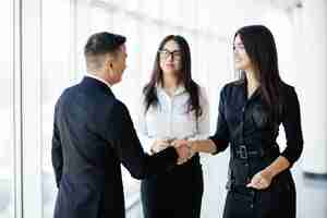 Free photo businessman and businesswoman shaking hands in office hall at informal meeting