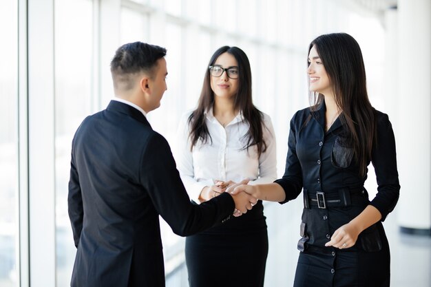 Бизнесмен и деловая женщина, пожимая руки в офисном зале на неформальной встрече