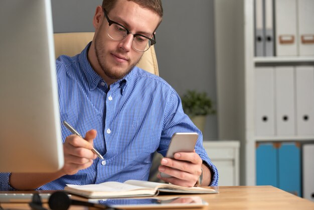 Businessman checking reminder app on the phone and diary