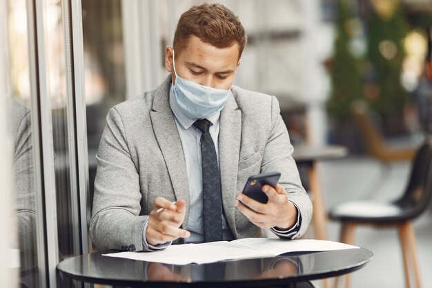 Free photo businessman in a city. person in a mask. guy with documents and phone;