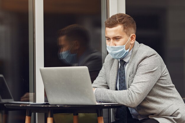 Businessman in a city. Person in a mask. Guy with laptop.