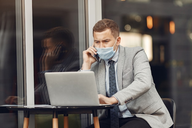 Uomo d'affari in una città. persona in maschera. ragazzo con laptop.