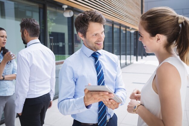 Businessman and colleague discussing over digital tablet