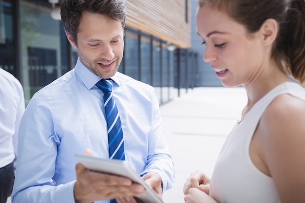 Businessman and colleague discussing over digital tablet