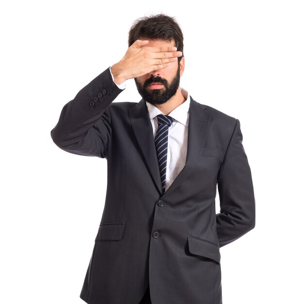 Businessman covering his eyes over isolated white background