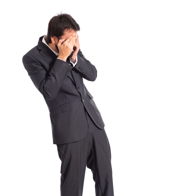 Businessman covering his eyes over isolated white background