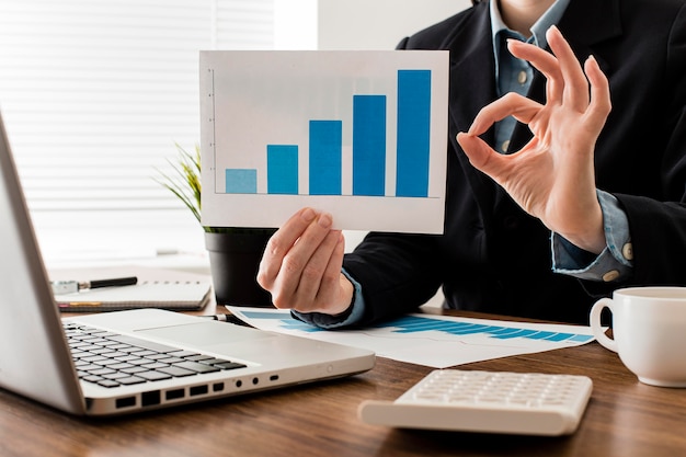 Businessman doing the ok sign while holding growth chart