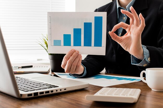 Businessman doing the ok sign while holding growth chart