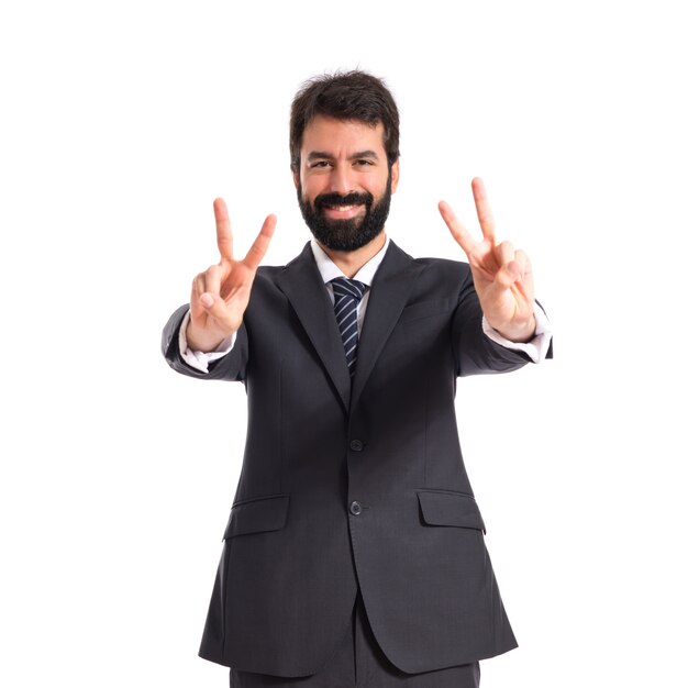 Businessman doing victory gesture over white background