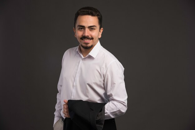 A businessman in dress code holding a black jacket in his arm. 