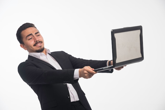 A businessman in dress code holding a laptop and having online meeting. 