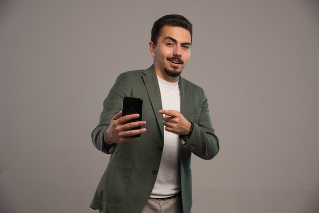 A businessman in dress code promoting a smartphone. 