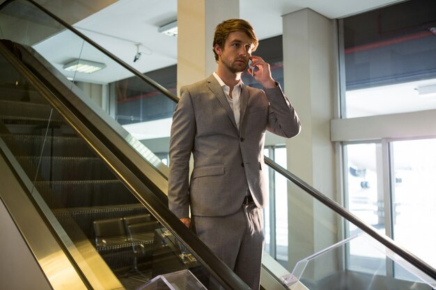 Businessman on escalator talking on mobile phone