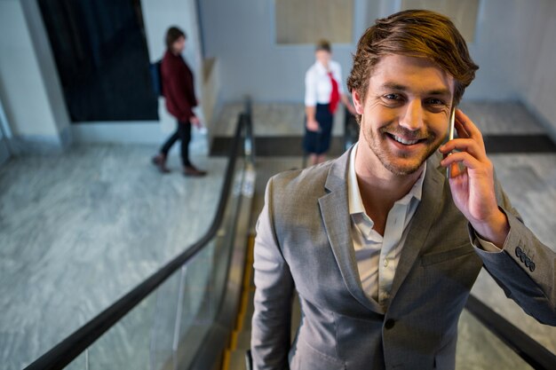 Businessman on escalator talking on mobile phone