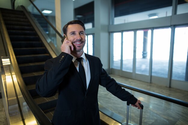 Businessman on escalator talking on mobile phone