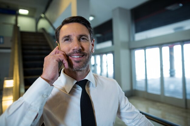 Businessman on escalator talking on mobile phone
