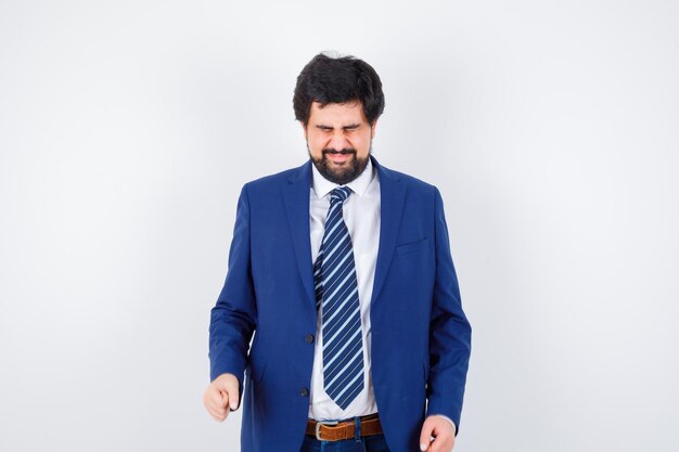 Businessman in formal suit clenching fists and looking harried , front view.