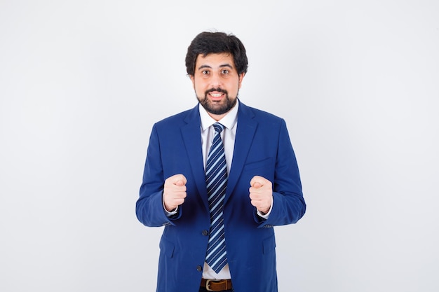 Businessman in formal suit clenching fists and looking harried , front view.