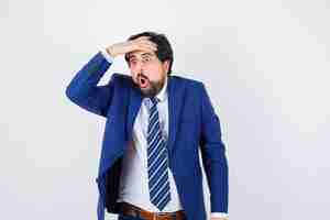 Free photo businessman in formal suit holding hands on forehead and looking surprised , front view.