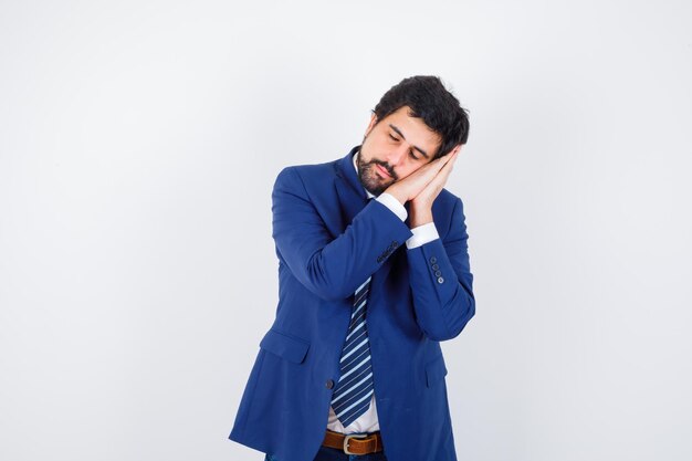 Businessman in formal suit leaning cheek on hands and looking sleepy , front view.