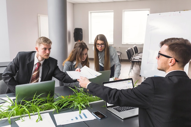 Businessman giving document to his colleague at workplace